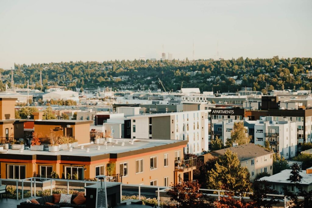 High-angle view of a city neighborhood with mid-rise apartment buildings and distant forested hills.