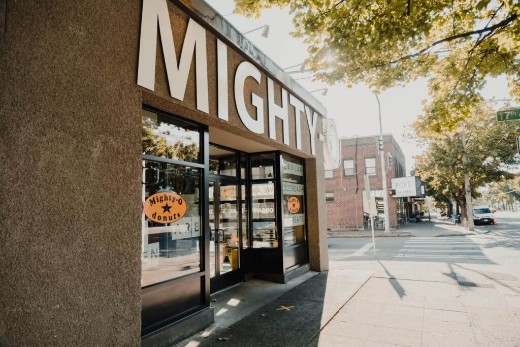 The storefront of a Mighty-O Donuts shop on a city street corner.