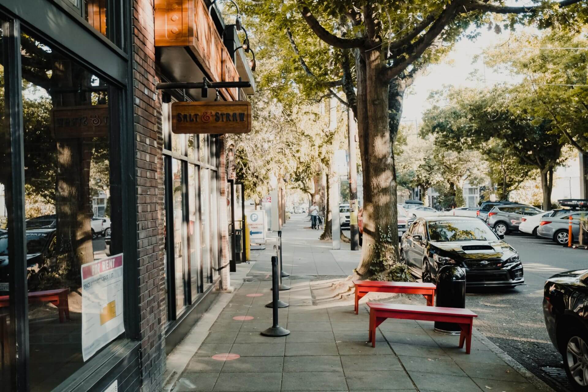 The Salt & Straw ice cream shop storefront with a red bench on the sidewalk and a For Rent sign in the window.